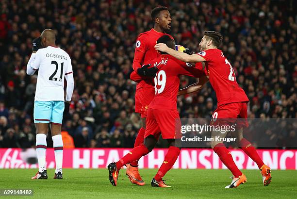 Angelo Ogbonna of West Ham United looks dejected as Divock Origi of Liverpool celebrates with Adam Lallana and Sadio Mane as he scores their second...