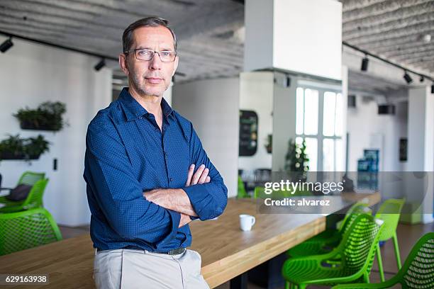 successful senior businessman standing in office - older man in office stockfoto's en -beelden