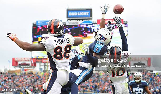 Demaryius Thomas and Emmanuel Sanders of the Denver Broncos fight against LeShaun Sims of the Tennessee Titans to try to make a reception in the end...