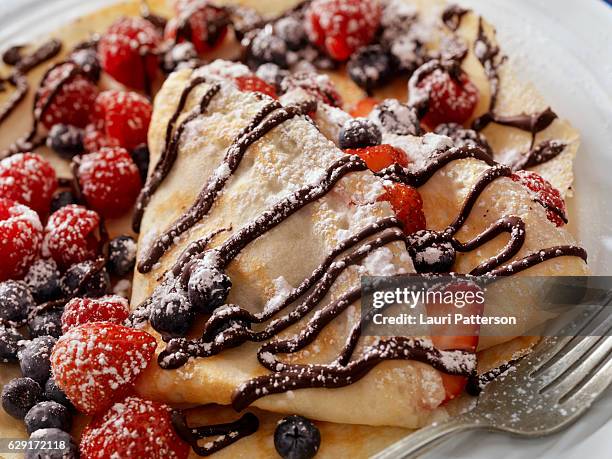 crepes with fresh berries, chocolate sauce and powdered sugar - chocolate spread stock pictures, royalty-free photos & images