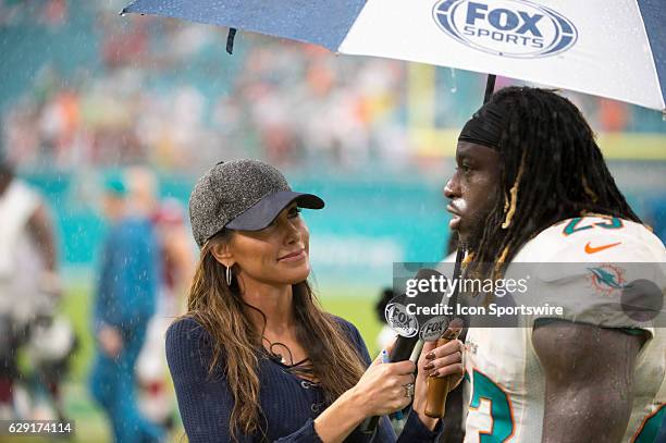 Sports field reporter Holly Sonders interviews Miami Dolphins Running Back Jay Ajayi in the rain on the field after the NFL football game between the...