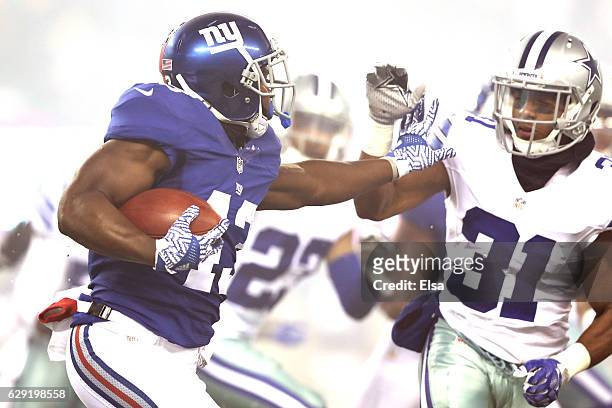 Bobby Rainey of the New York Giants stiff arms Byron Jones of the Dallas Cowboys during the first quarter of the game at MetLife Stadium on December...