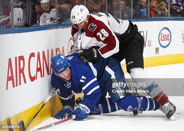 Zach Hyman of the Toronto Maple Leafs and Patrick Wiercioch of the Colorado Avalanche battle behind the net during the third period at the Air Canada...