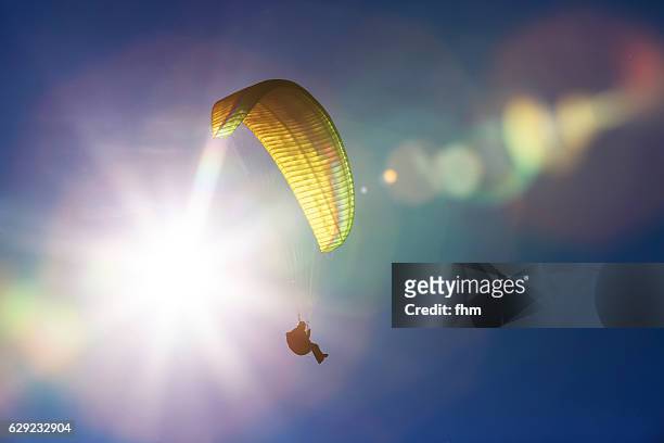 paraglider in the sky with sunlight and reflections - gleiten stock-fotos und bilder