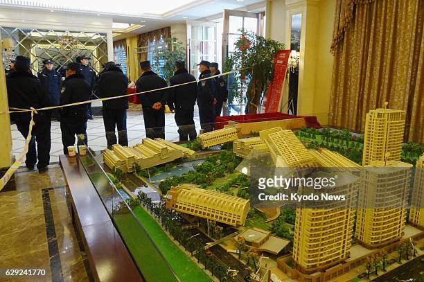 China - Security guards stand in front of a damaged miniature model of a condominium complex in Hangzhou, China on Feb. 26 after people who bought...