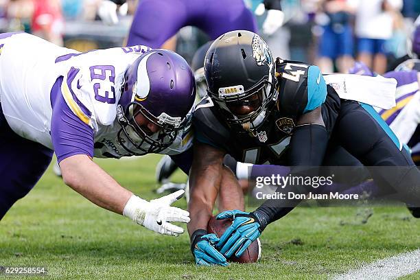 Guard Brandon Fusco of the Minnesota Vikings and Safety Jarrod Wilson of the Jacksonville Jaguars dive for a fumble during the game at EverBank Field...