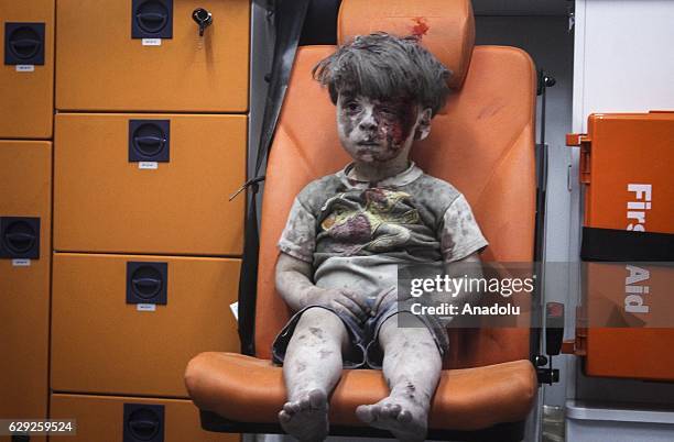 Year-old wounded Syrian kid Omran Daqneesh sits alone in the back of the ambulance after he got injured during Russian or Assad regime forces air...