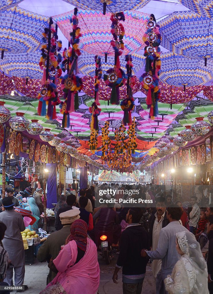 Pakistani devotee people decorating a market with colorful...