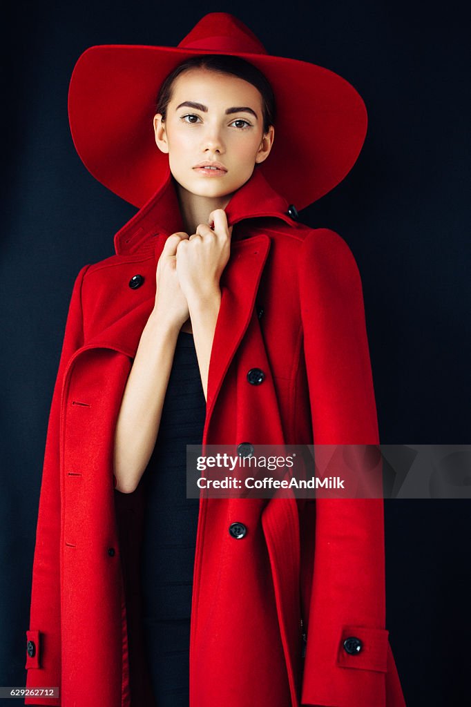 Beautiful girl with make-up wearing red coat and hat