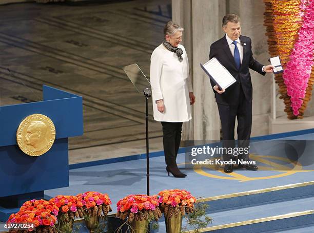 Colombian President Juan Manuel Santos poses with the Nobel Peace Prize medal and diploma at the City Hall in Oslo on Dec. 10, 2016. Santos was...