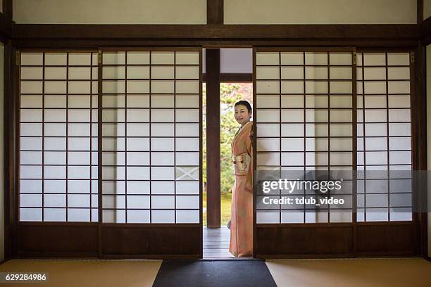 mujer en kimono mirando a través de puertas correderas en un templo - shoji fotografías e imágenes de stock