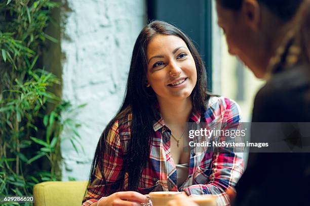 girl friends sitting together in cafe, chatting, drinking coffe - publik stockfoto's en -beelden