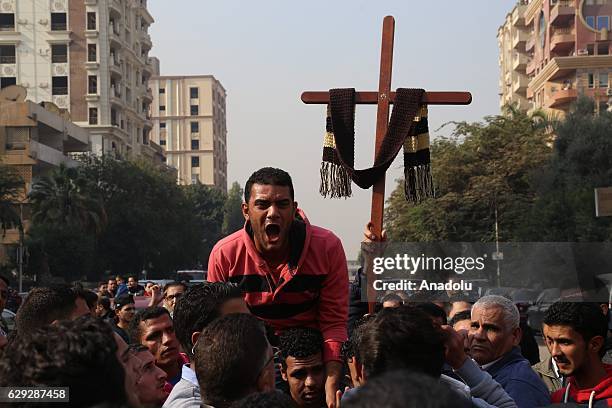 People react during the funeral ceremony for the victims of the explosion at Saint Peter and Saint Paul Coptic Orthodox Church in Abbasiya district,...