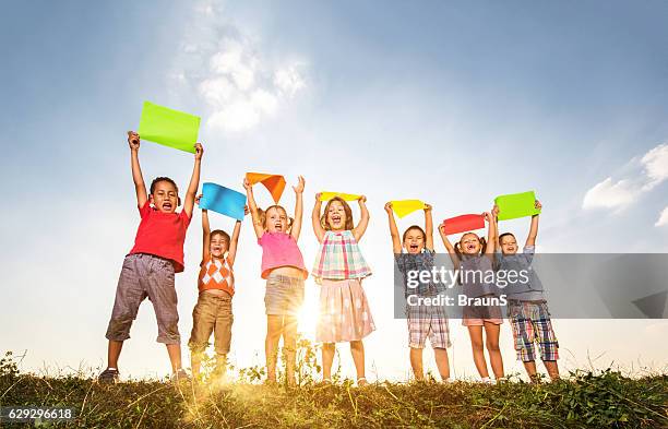 unter dem blick auf fröhliche kinder mit bunten papieren in der natur. - holding aloft stock-fotos und bilder