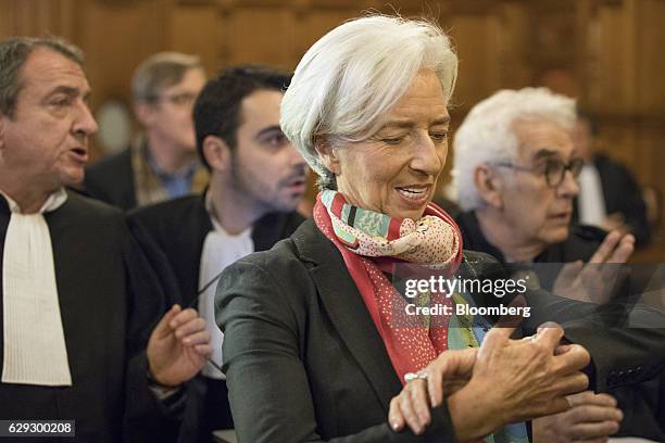 Christine Lagarde, managing director of the International Monetary Fund , center, checks her watch whilst standing inside the courtroom and next to...