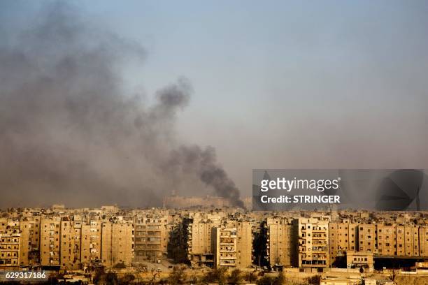 Smoke billows from the former rebel-held district of Bustan al-Qasr in Aleppo, on December 12 during an operation by Syrian government forces to...