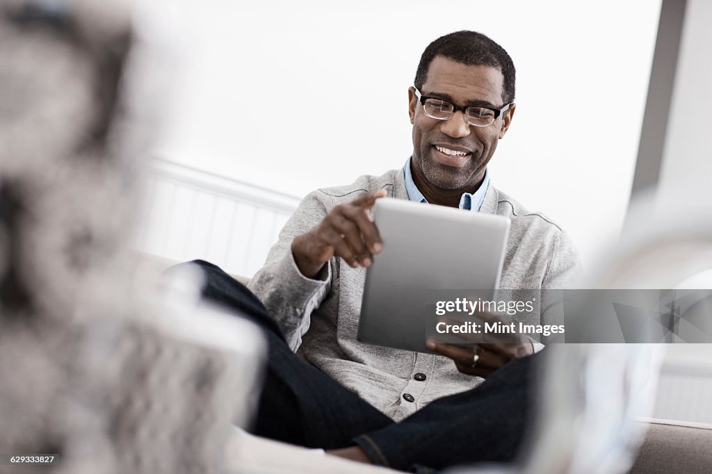A man sitting on a sofa, using a digital tablet.