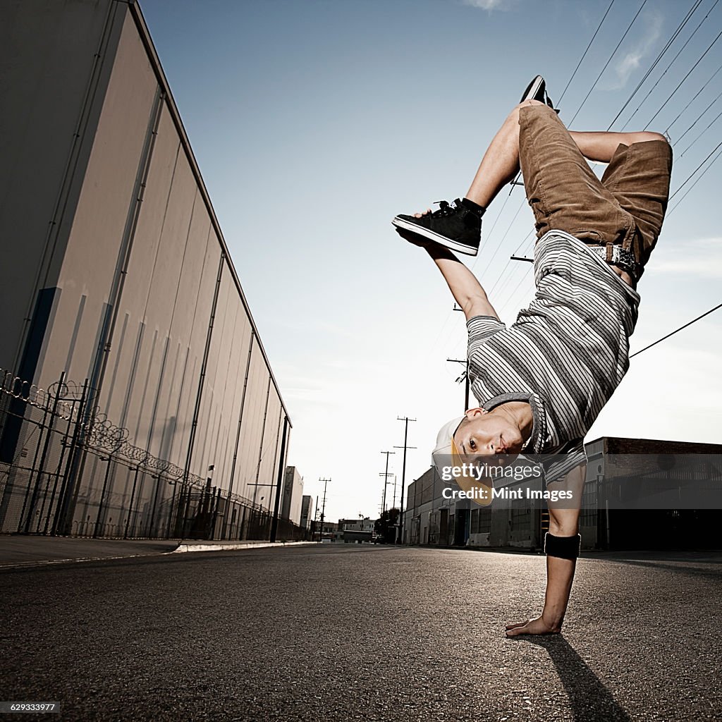 A young person with a boombox on the street of a city.