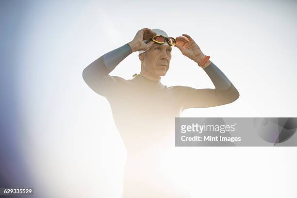 a swimmer in a wetsuit and swimming hat, adjusting his swimming goggles.  - simglasögon bildbanksfoton och bilder
