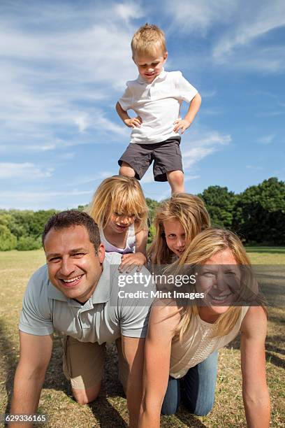 family with three children playing in a park. - human pyramid foto e immagini stock