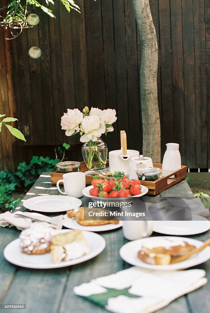 Breakfast table with tea, pastries and fresh strawberries.