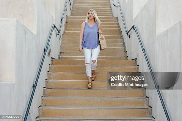 blond woman walking down a staircase. - down blouse ストックフォトと画像