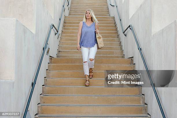 blond woman walking down a staircase. - down blouse imagens e fotografias de stock