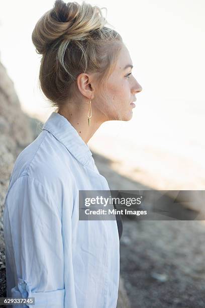 profile portrait of a blond woman with a hair bun. - summer hair bun stock pictures, royalty-free photos & images