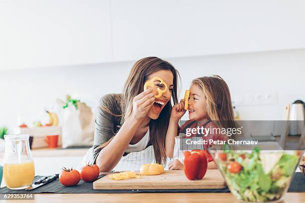 mother and daughter having fun with the vegetables - mom and young daughter stockfoto's en -beelden