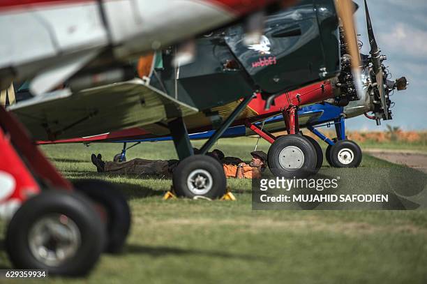 Pilots rest under their aircrafts after they landed at Baragwanath airfield as part of the Vintage Air Rally airshow.on December 12, 2016. A dozen...