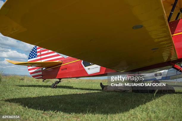 Pilot rests under an aircraft at the Baragwanath airfield as part of the Vintage Air Rally airshow.on December 12, 2016. A dozen biplanes from the...