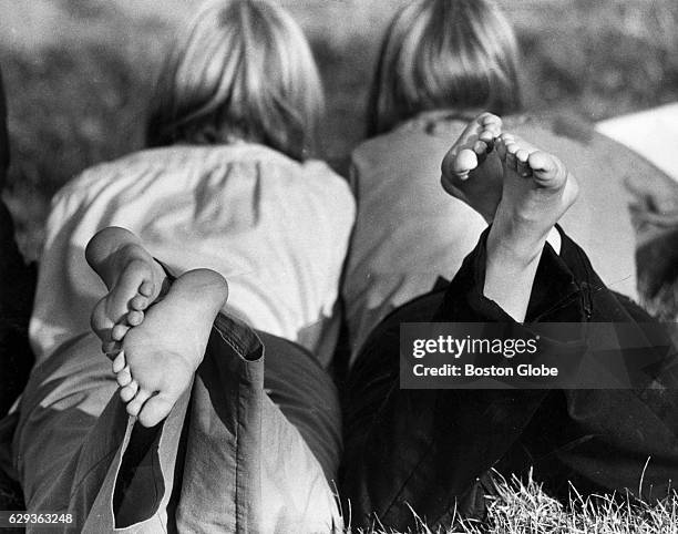 Laura Gardner and Alexandra McGovern, both of Groton, Mass., relax in the grass along the Charles River near Soliders Field Road in Cambridge, Mass....