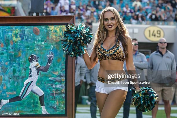 Member of The Roar, the cheerleading squad for the Jacksonville Jaguars, poses with a painting of former Jacksonville Jaguars wide receiver Jimmy...
