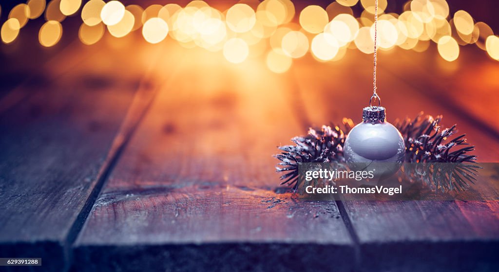 Hängende Weihnachtsschmuck auf altem Holz und defokussierte gold Lichter