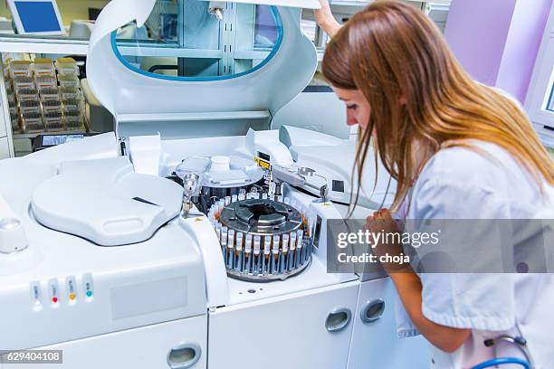 lab scientist placing test tubes with blood samples in centrifuge - blood type stock pictures, royalty-free photos & images