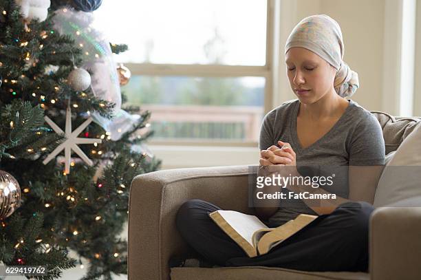 ethnic young female cancer patient reading the bible and praying - healing prayer images stock pictures, royalty-free photos & images
