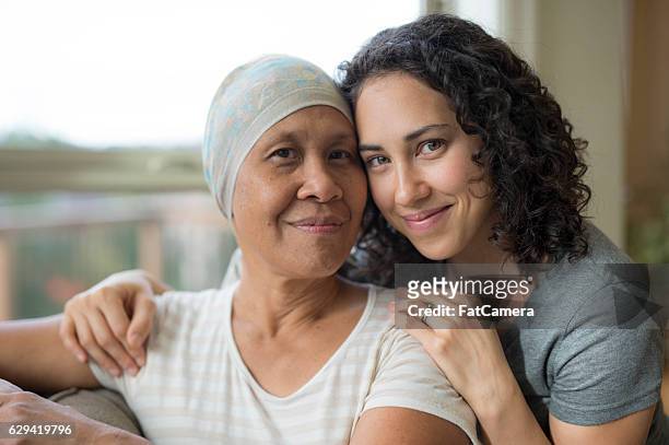 ethnic young adult female hugging her mother who has cancer - all you need is love stockfoto's en -beelden