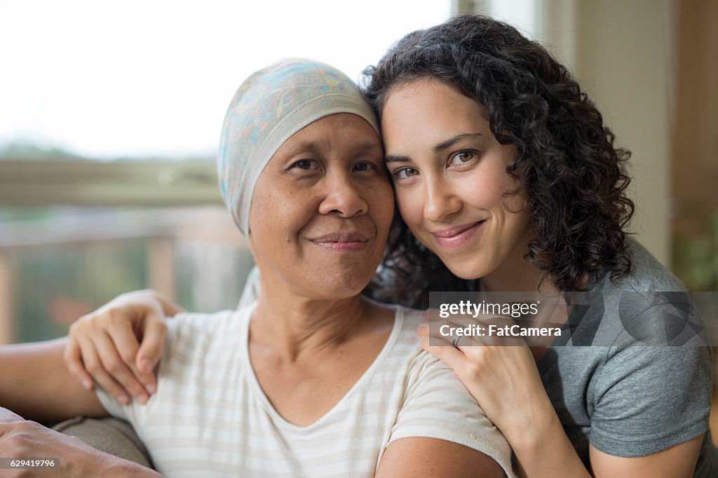 Ethnic young adult female hugging her mother who has cancer