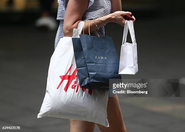Shopper carries shopping bags by Zara, operated by Inditex SA, and Hennes & Mauritz AB in Sydney, Australia, on Saturday, Dec. 10, 2016. Australia is...
