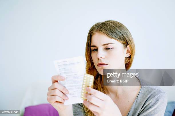 Woman reading contraceptive pill instruction sheet.