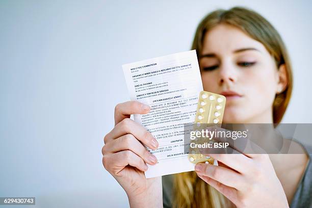 Woman reading contraceptive pill instruction sheet.