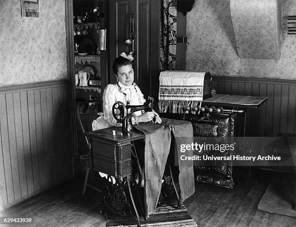 Woman Sewing Pants on Sewing Machine, circa 1905.