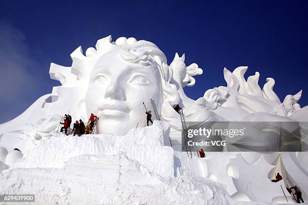 Artists carve the 103-meter-long snow sculpture "Long Song" for the 29th Harbin International Snow Sculpture Art Expo at Sun Island on December 13,...