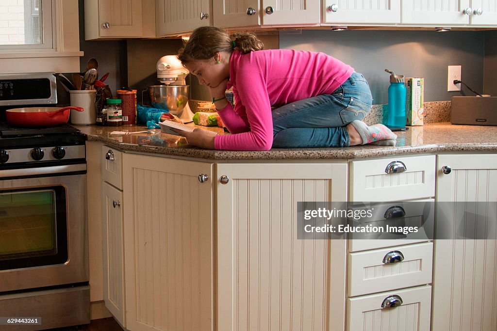 Pre-teen reads book on counter top