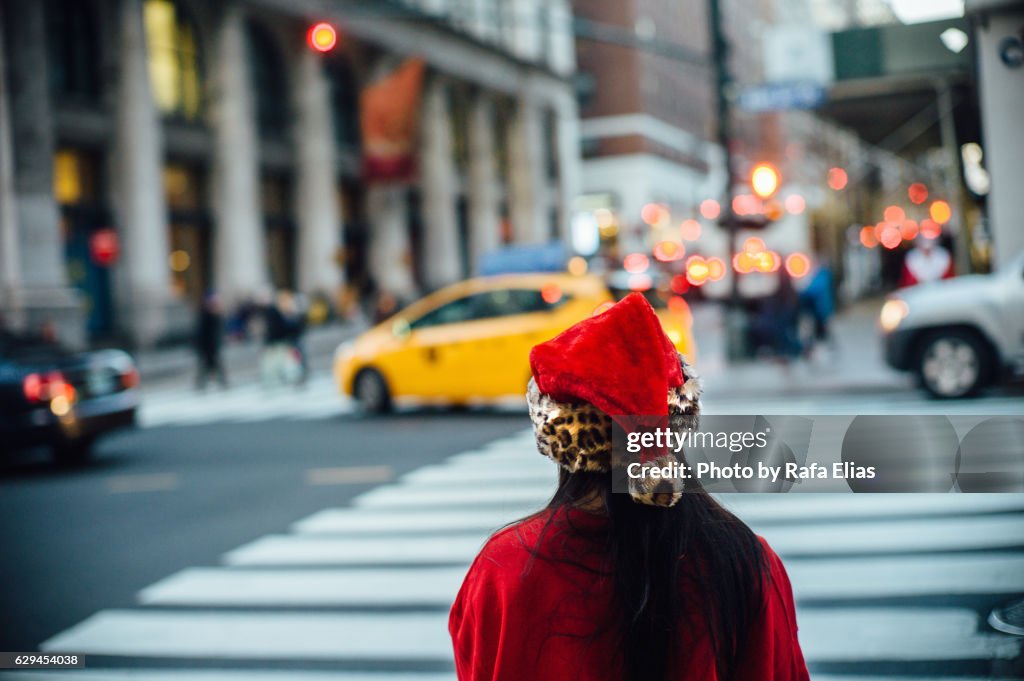Girl dressed as Santa Claus waiting at zebra crossing