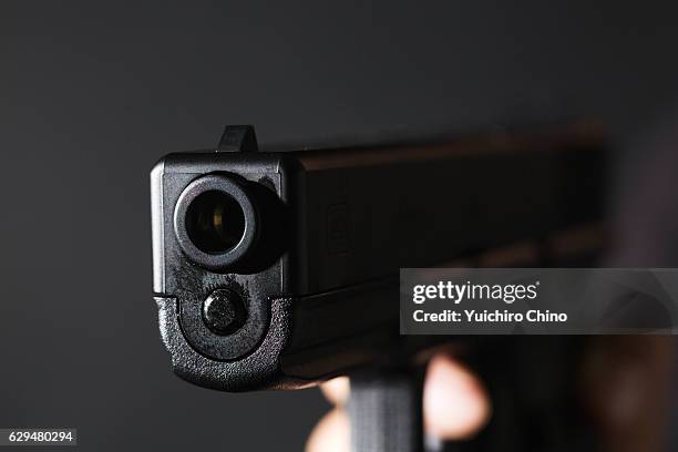 holding a gun on black background - abfeuern stock-fotos und bilder