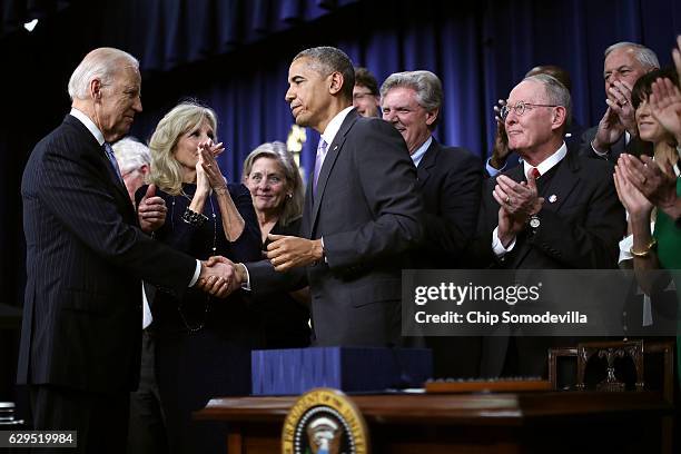Surrounded by advocates and lawmakers, U.S. President Barack Obama shakes hands with Vice President Joe Biden after signing the 21st Century Cures...