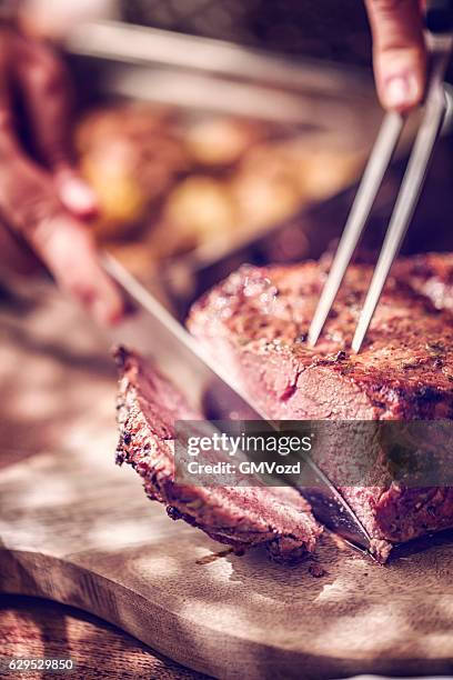 cutting roast beef with potatoes and root vegetables - roast beef stock pictures, royalty-free photos & images