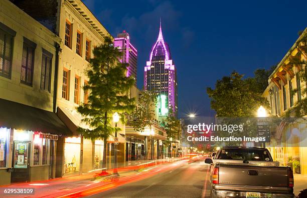 Mobile Alabama downtown traffic on Dauphin Street at twilight with Trustmark Skyscraper in the background at night.