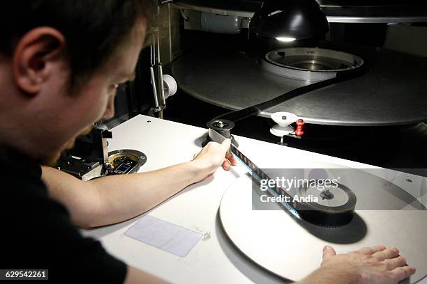 Cinema industry, projectionist. Handling of rolls of film in a video-screening room in a cinema complex. 35 mm film screening.